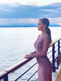 a woman in a purple dress standing on the deck of a cruise ship