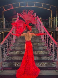 a woman in a red dress standing on a staircase